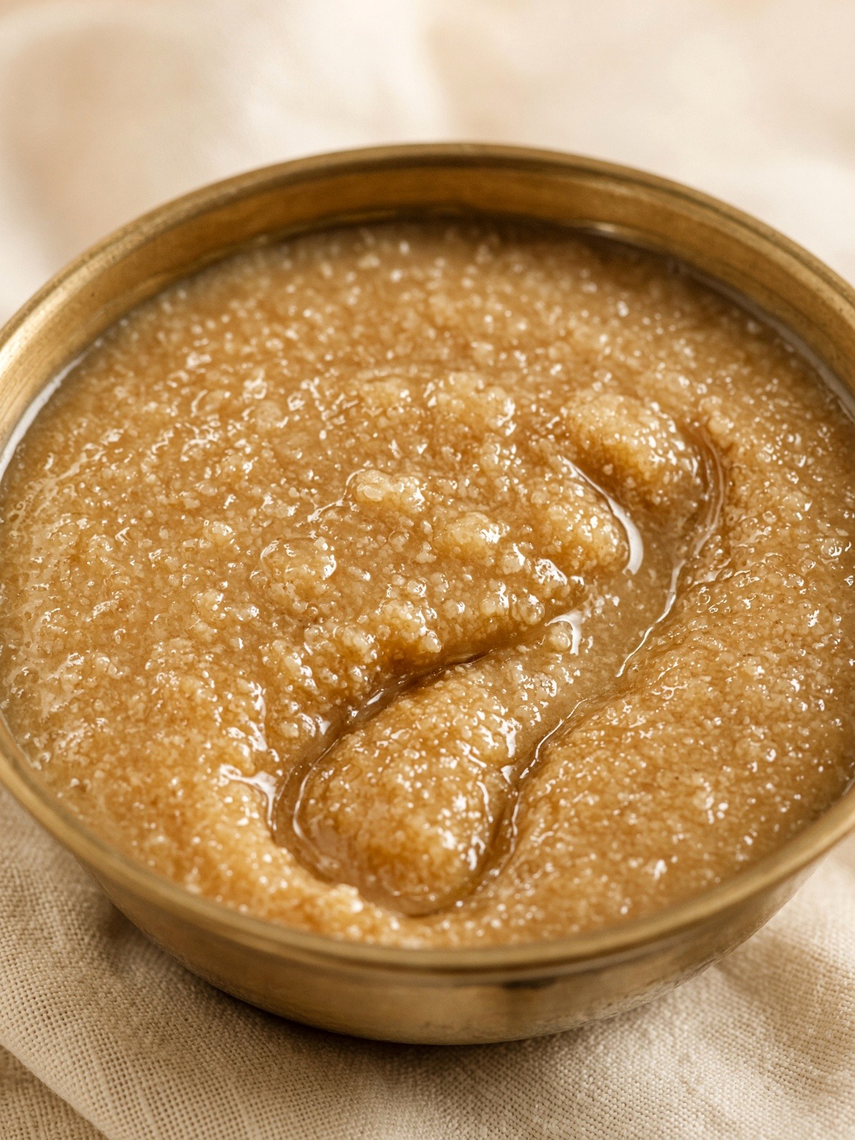 Oily beige-brown buffalo ghee with micro granules on a spoon